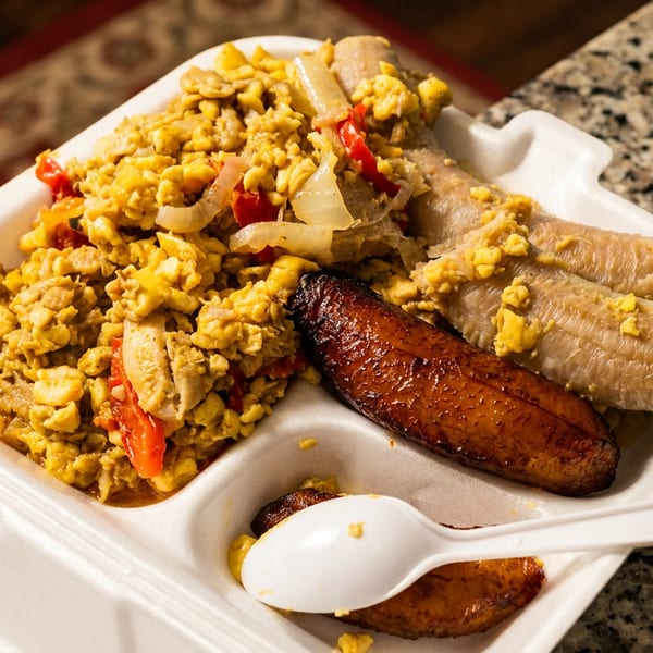 Ackee and saltfish with boiled and fried plantains in a white takeout container.