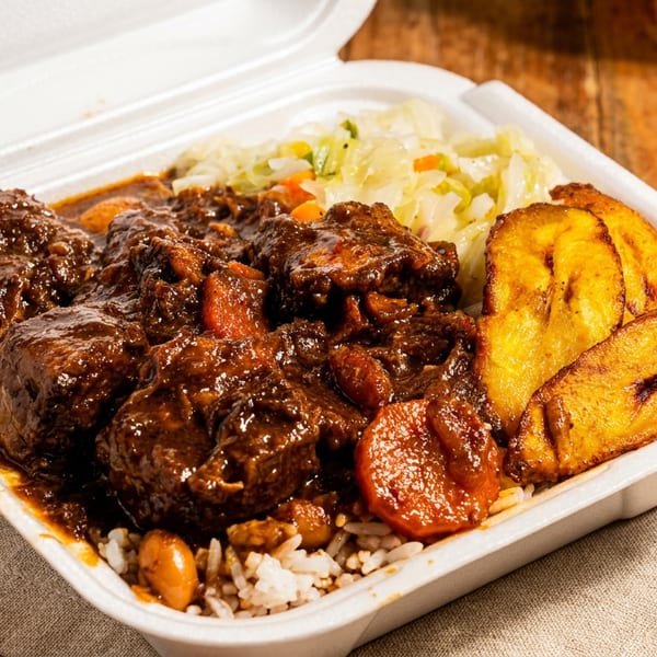 Oxtail stew with rice, cabbage, and fried plantains in a white takeout container on a wooden table.