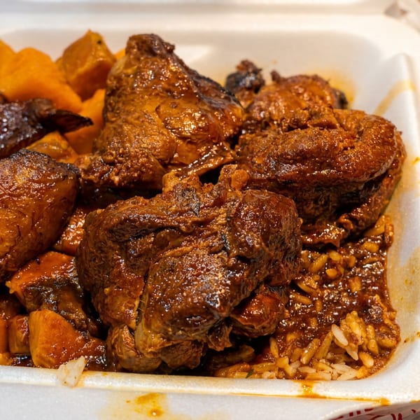 Stewed chicken and rice with cubed sweet potatoes in a white takeout container.